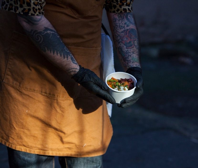 ABLF Chef holding a single portion of a daily meal recipe outside of 43 W Hastings where the meals are prepared.